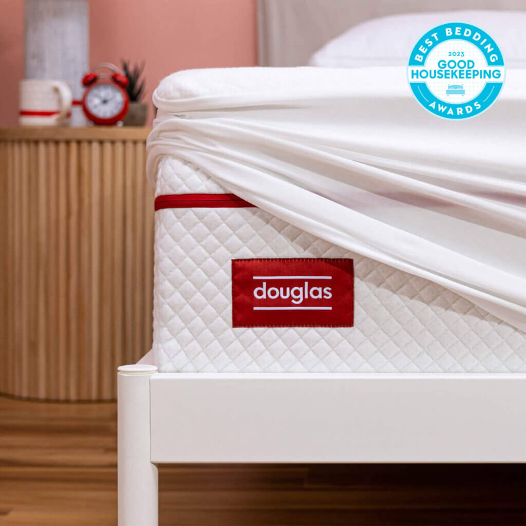 Douglas mattress with mattress protector pulled up to show the mattress. Also shows the Good Housekeeping Best Bedding Award.